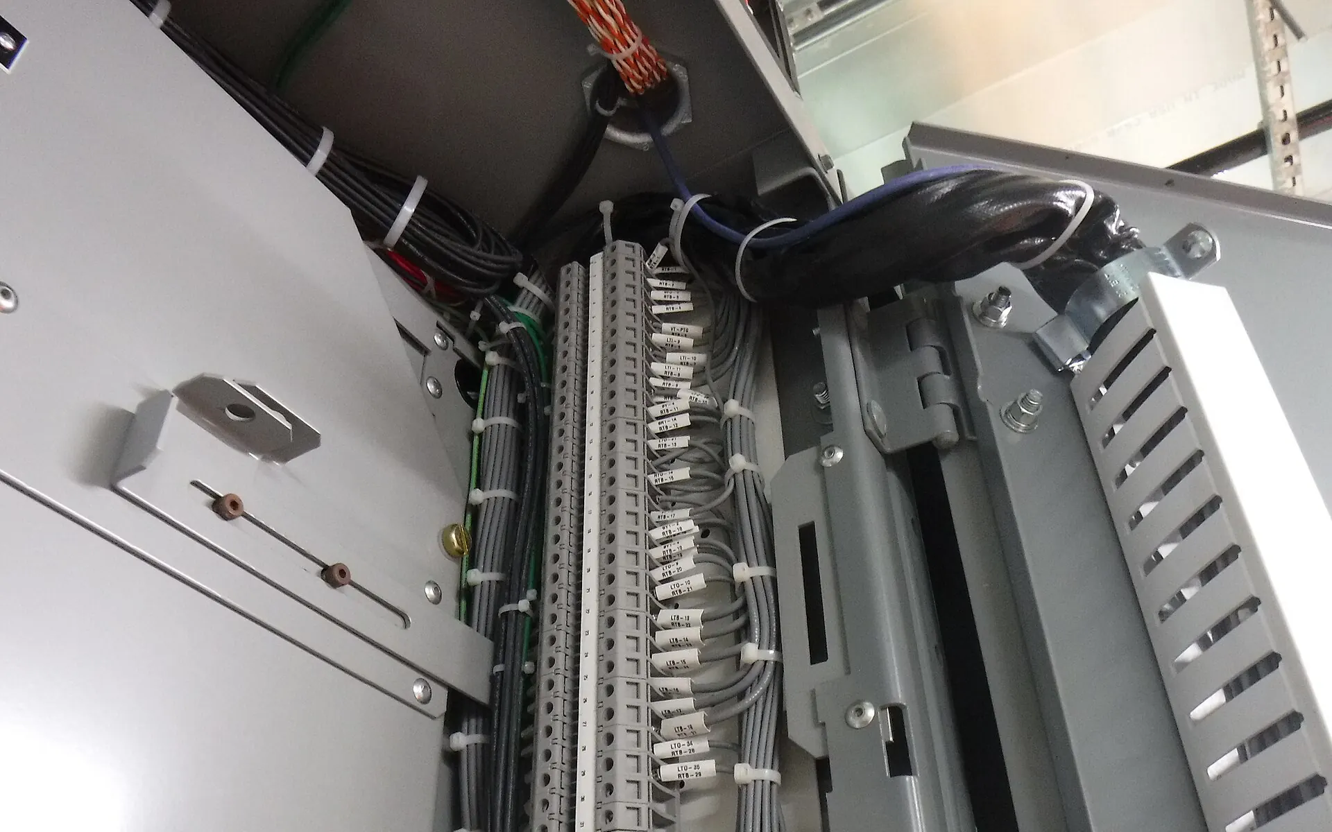 Técnico identificando y etiquetando cables de control dentro de un armario eléctrico